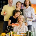Three generations of a family enjoying a festive celebration with gifts and a meal.