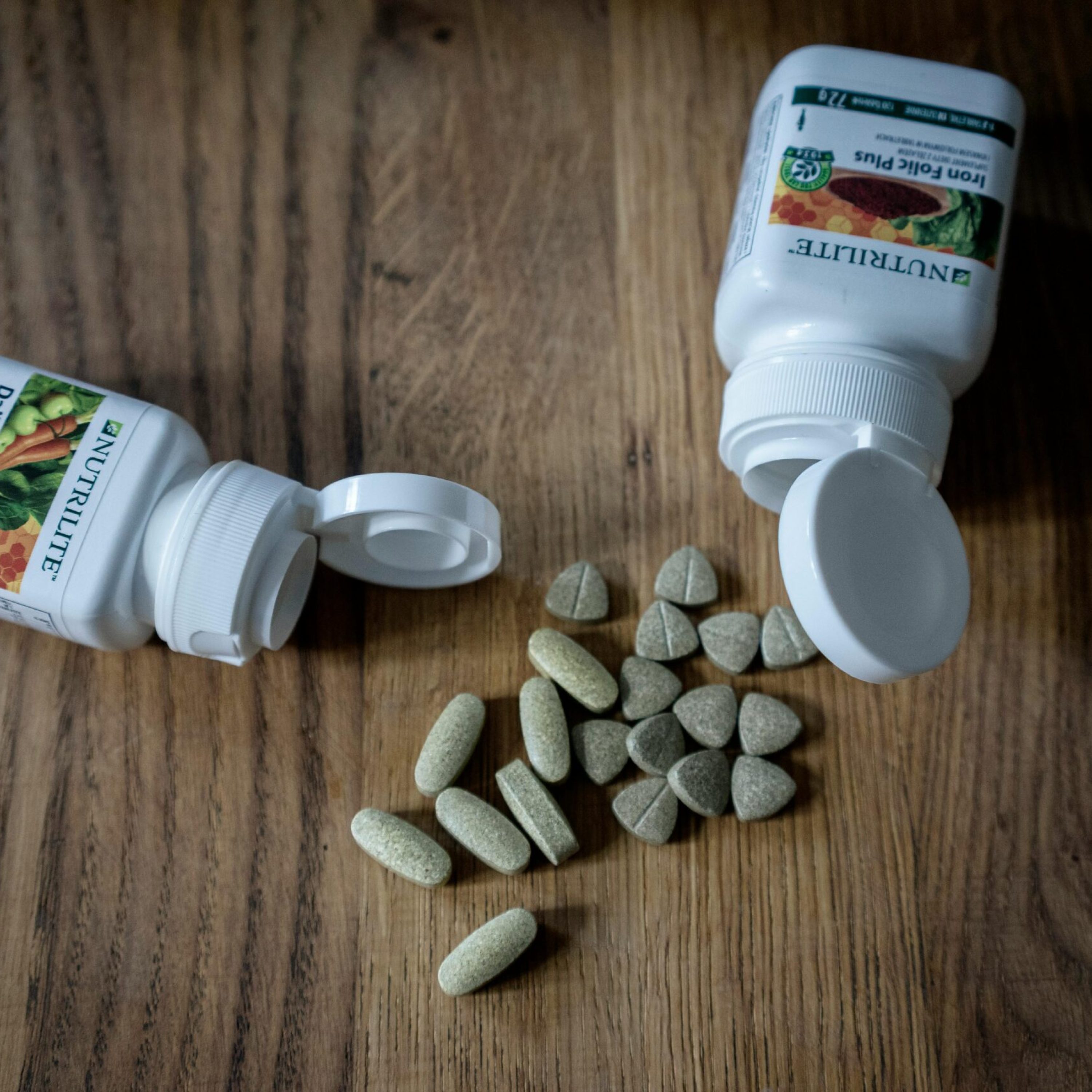 pexels-photo-4489303-4489303 Variety of supplements and vitamin pills with open containers on a wooden surface.